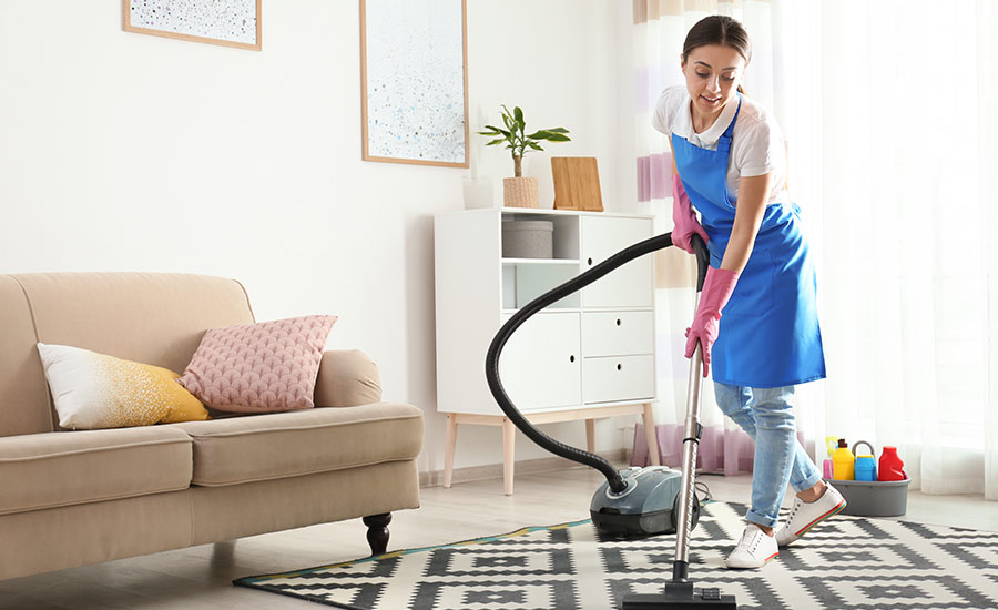 A professional cleaner vacuuming the carpet in a house​
