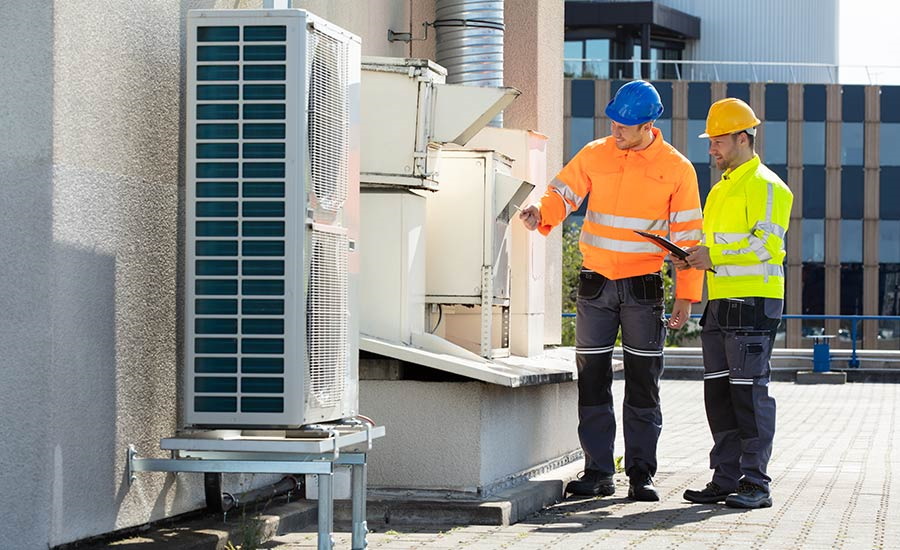 Technicians checking an A/C system on the roof of a building