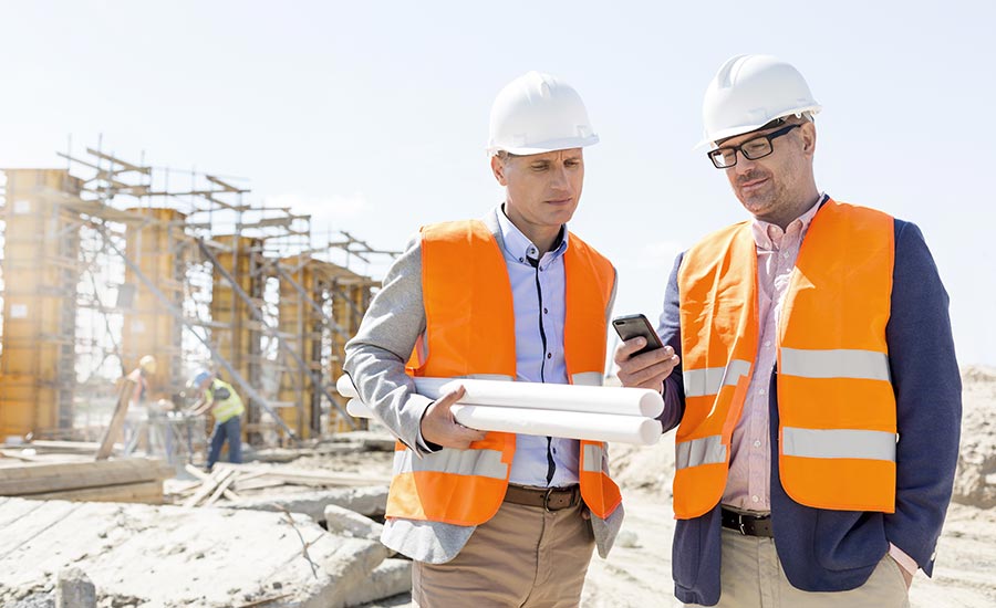 Two construction workers looking at an automated checklist