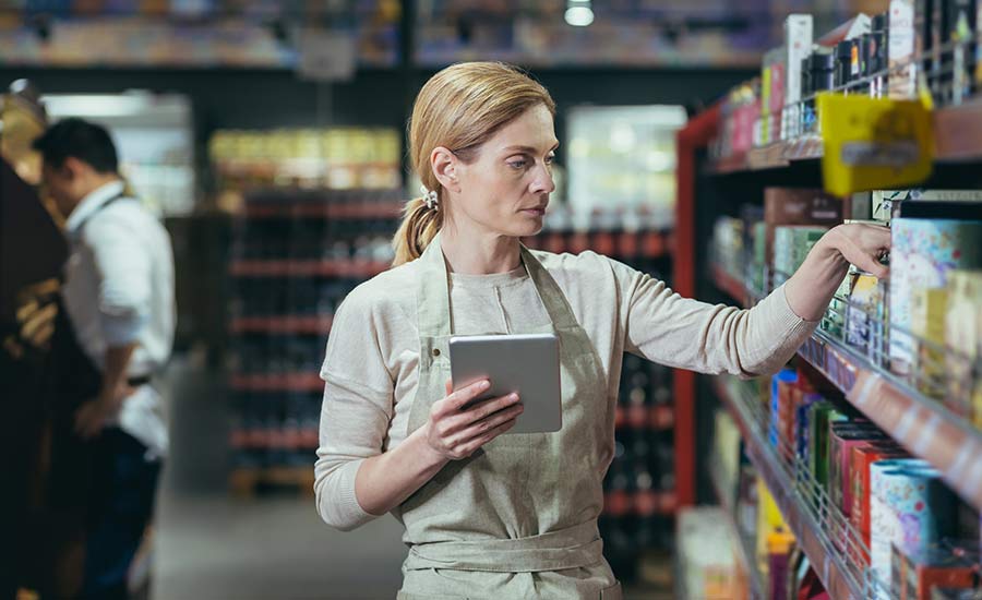 A grocery employee checking expiry dates on canned goods