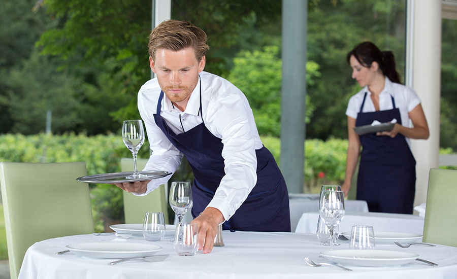 A male restaurant server setting the table in the alfresco station
