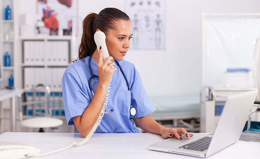 A female nurse using a telephone and laptop