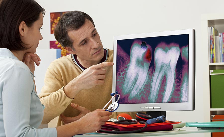 An image of a dental office manager showing x-ray results to a patient​