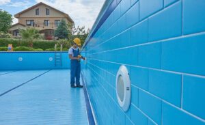 A pool worker examines the systems in an empty pool​