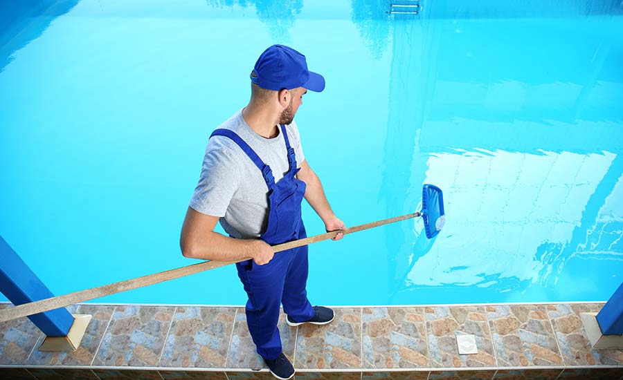 A pool employee cleaning a swimming pool