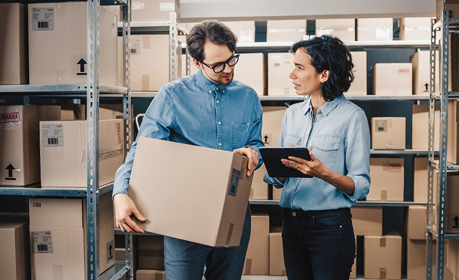 Warehouse employees looking at a tablet ​