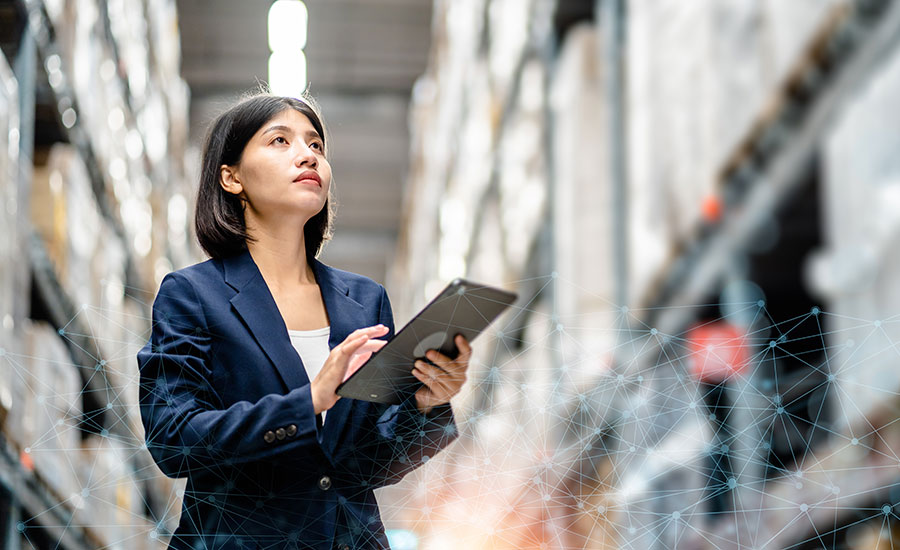 A woman in a warehouse creating work orders on a tablet​