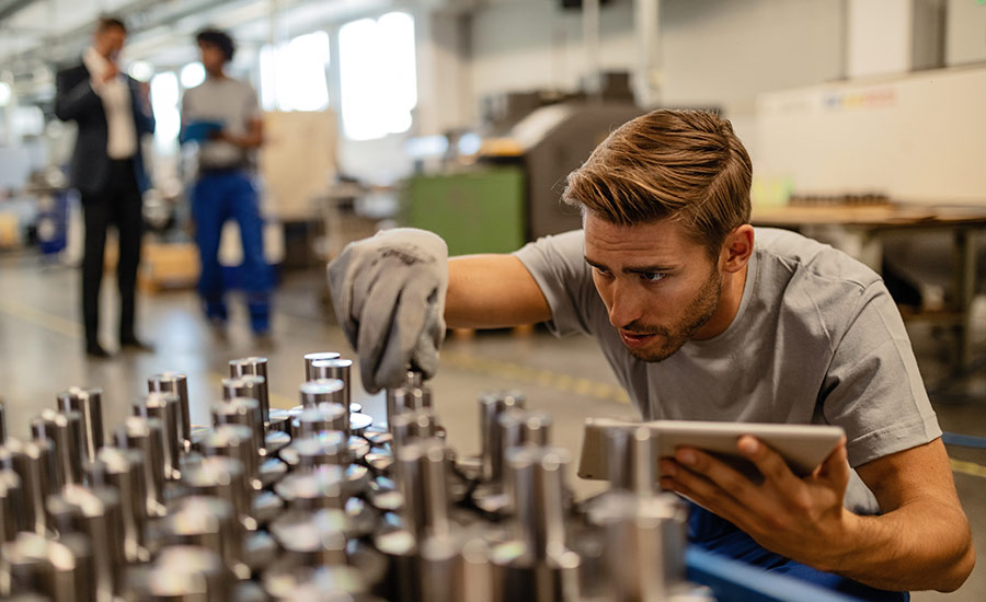 A steel factory worker checking manufactured rod cylinders and filling in a QC checklist​