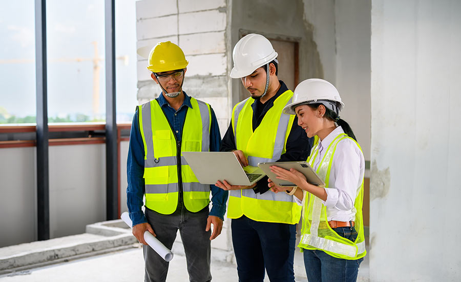 Three construction employees looking at a laptop screen​