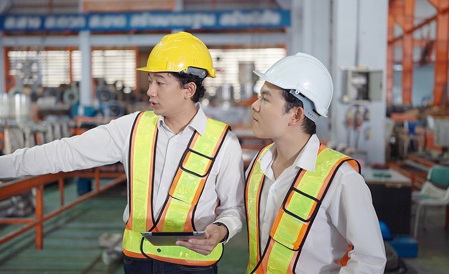An Asian engineer conducting a training with a tablet in his hand​