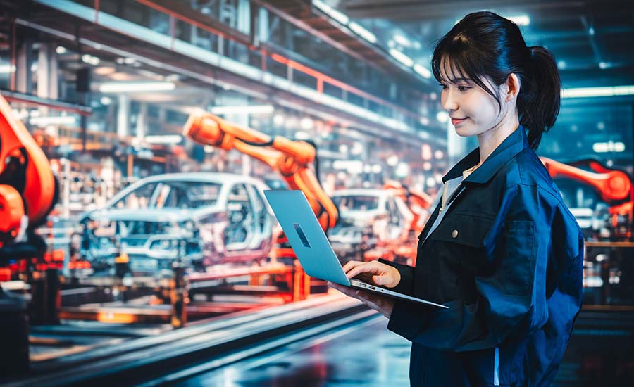 A young woman with a laptop at a factory production line